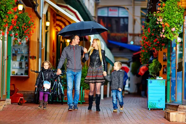 stock image Happy family walking under the rain on cozy colorful street