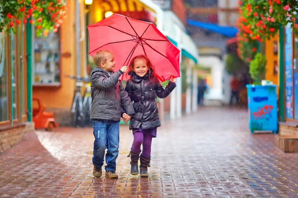 Glückliche Kinder laufen im Regen auf der bunten Straße — Stockfoto