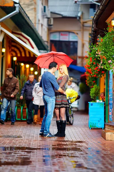 Pár v lásce, stojící v dešti na barevné ulice — Stock fotografie