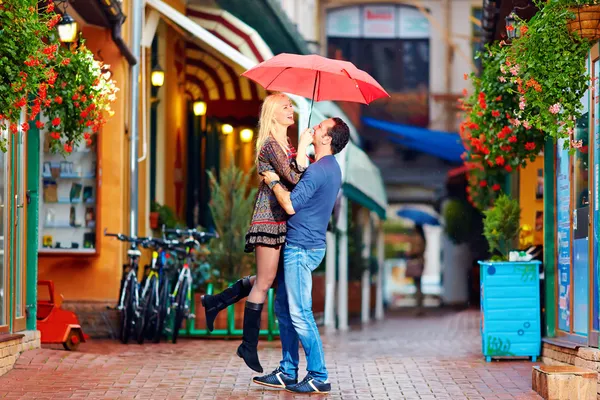 Счастливая влюбленная пара обнимается на красочной улице — стоковое фото