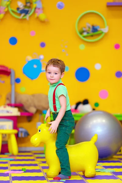 Bambino felice cavalcando un giocattolo nella scuola materna — Foto Stock