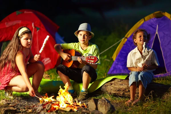Gece kamp ateşi etrafında mutlu gençler — Stok fotoğraf