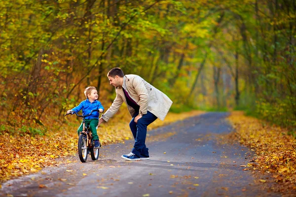 Vader leert zoon fietsen op de fiets — Stockfoto