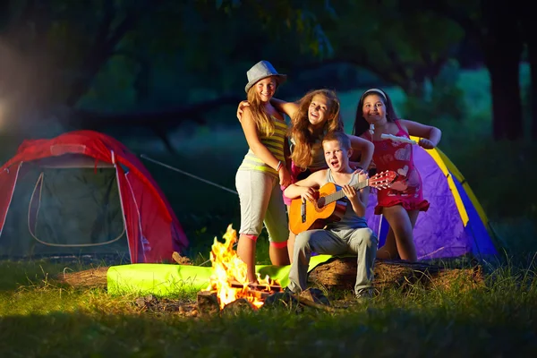 Adolescentes felizes juntos em torno da fogueira de acampamento — Fotografia de Stock