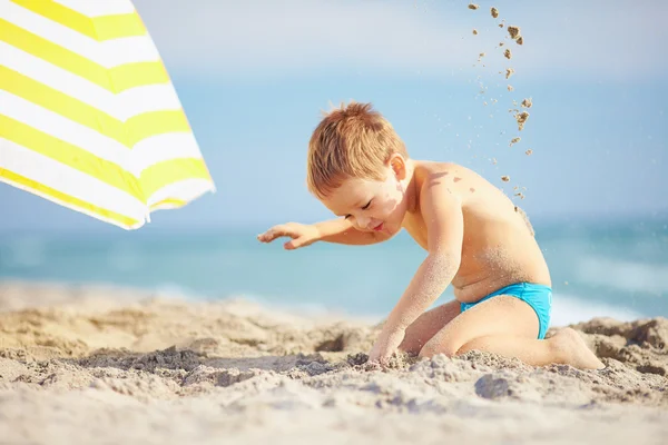 Menino feliz, brincando na areia da praia — Fotografia de Stock