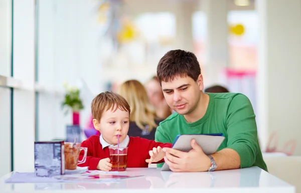 Батько і син з планшетом у барвистому кафе — стокове фото
