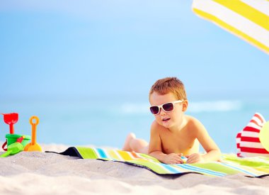 ładny chłopiec dziecko opalając się na plaży