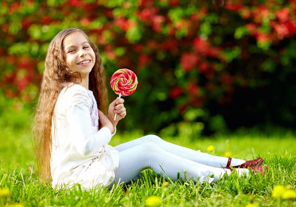Красива дівчина з барвистими цукерками в парку — стокове фото