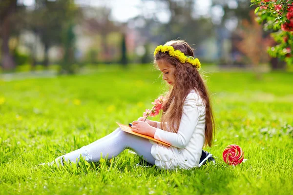 Cute girl reading book, sitting on spring lawn — Stock Photo, Image