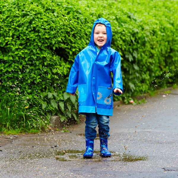 Funny happy kid jumping in puddles — Stock Photo, Image