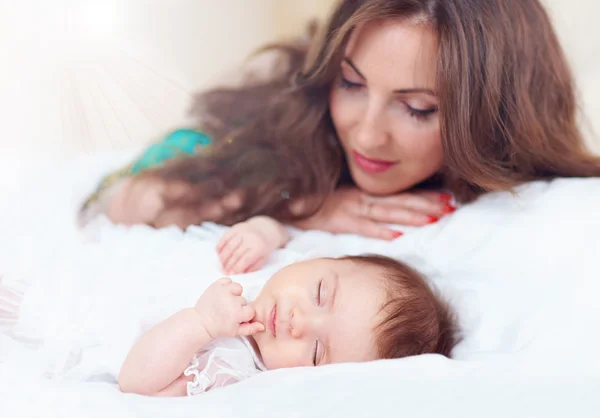 Vacker mor tittar på nyfödda dotter sover — Stockfoto