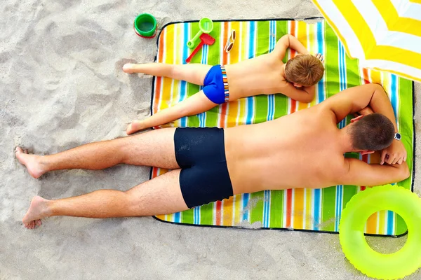 Pai e filho tomando banho de sol em cobertor colorido — Fotografia de Stock
