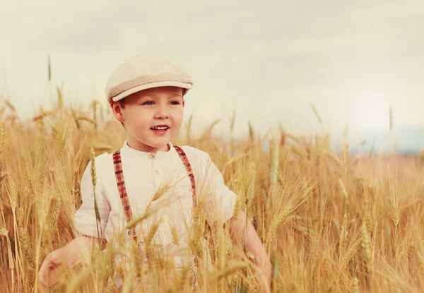 Glücklicher Junge, der über das Weizenfeld geht — Stockfoto