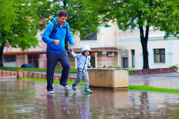 Feliz pai e filho correndo sob a chuva — Fotografia de Stock