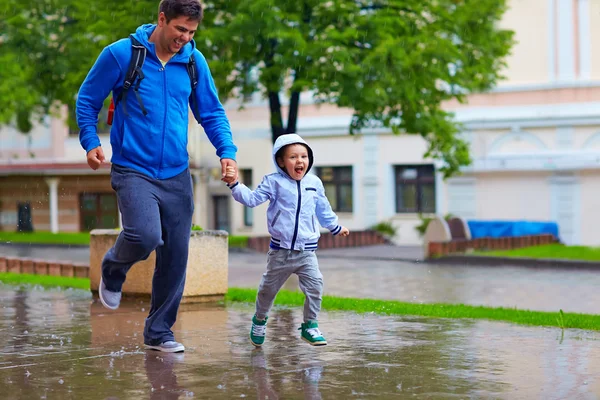 Feliz padre e hijo corriendo bajo la lluvia — Foto de Stock