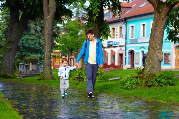 Otec a syn pěší ulici město po dešti — Stock fotografie