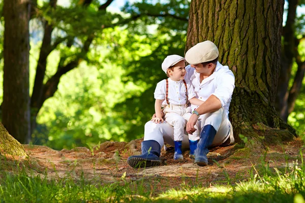 Pai e filho sentado sob uma árvore velha — Fotografia de Stock