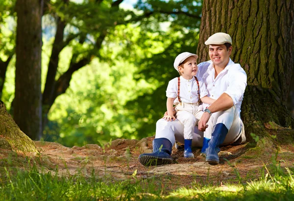 Father and son sitting under an old tree — Stock Photo, Image