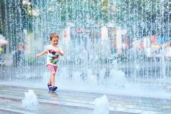 Chico excitado corriendo entre el flujo de agua en el parque de la ciudad —  Fotos de Stock