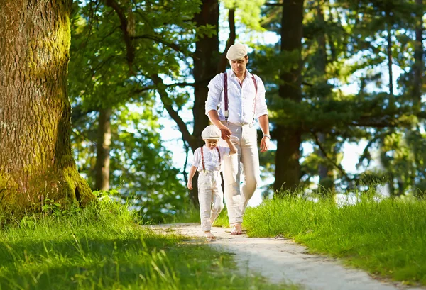 Pai e filho andando o caminho iluminado pelo sol da floresta — Fotografia de Stock