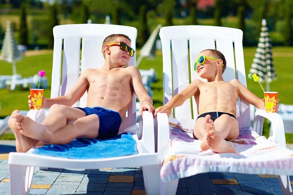 Teenage boys relaxing on sunbeds in waterpark — Stock Photo, Image