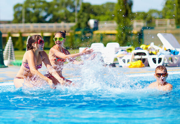 счастливые дети-подростки, плещущие воду в бассейне
