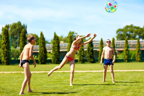 Groupe d'adolescents jouant avec le ballon sur la pelouse d'été — Photo