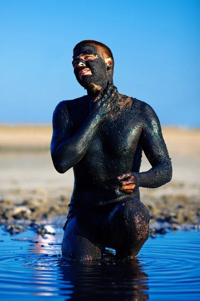 Man applying black healing clay outdoors — Stock Photo, Image