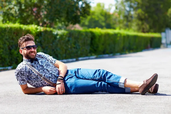 Cheerful young adult man lying on the road — Stock Photo, Image