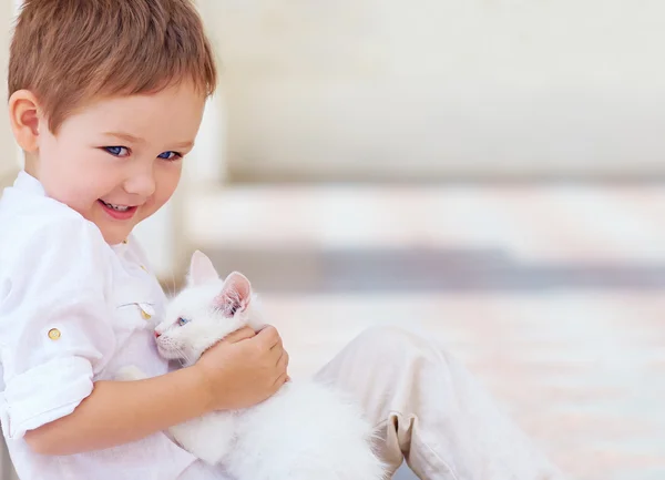 Niño feliz sosteniendo lindo gato blanco — Foto de Stock