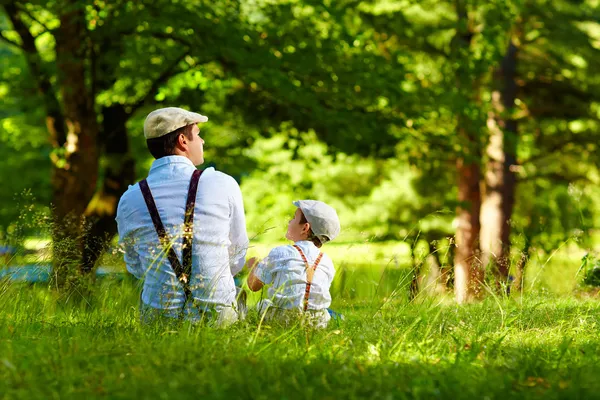 Père et fils assis sur la pelouse de la forêt — Photo