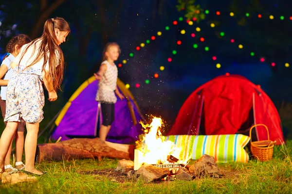 Crianças jogando madeira na fogueira, acampamento de verão — Fotografia de Stock