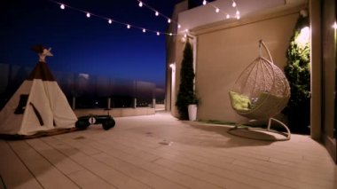 Çocuklar evdeki sıcak yaz akşamında çatıdaki terasta oyuncak çadırında oynuyorlar.