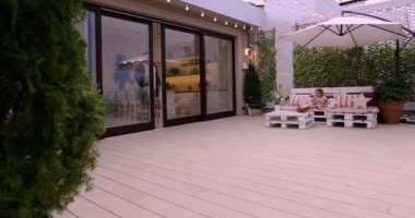 Adam sürgülü kapılar açıyor, terasa çıkıyor, rahat bir dinlenme odası var.