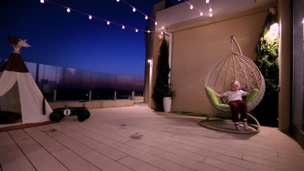 Kid Relaxing Hanging Chair Having Fun Rooftop Patio Summer Evening — Stock Video