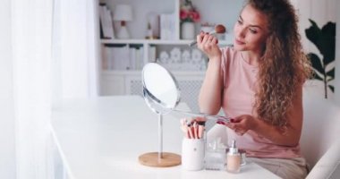 Evinden güzellik bloğu yayınlayan genç bir kadın, çevrimiçi içerik yaratıcısı makyaj yapıyor, video eğitmeni