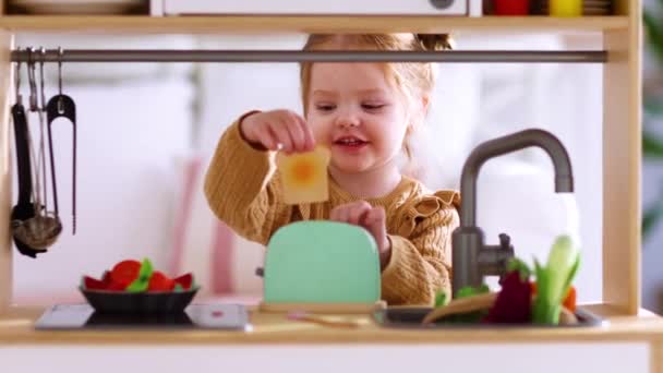 可爱的小女孩在玩具厨房里玩耍 假装在阳光灿烂的日子做好吃的面包 — 图库视频影像