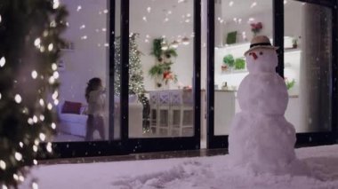 Bebek kışın kar yağarken modern apartmanın sürgülü kapılarını açıyor.