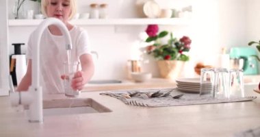 Genç bir çocuk bardağa musluk suyu dolduruyor, saf içme suyu.