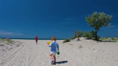 Küçük bir çocuğu kumsalda takip etmek, yaz etkinliği.