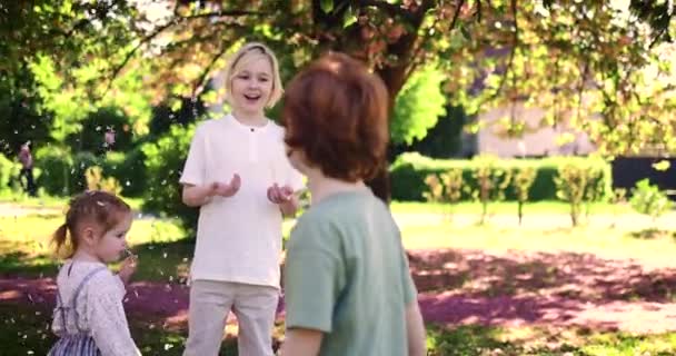 Niños Divirtiéndose Bajo Lluvia Flores Parque Primavera Día Soleado — Vídeo de stock