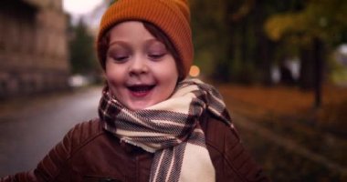 Mutlu genç bir çocuk, neşeli bir çocuk Sonbahar Şehri caddesinde yürüyüşe çıkmış.