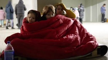 Bir grup küçük çocuk, hava saldırısı sırasında tahta paletin üzerinde sığınakta sessizce oturan kardeşler. Dondurucu gecede bir battaniyeyi paylaşmak. Rus istilası Ukrayna 'ya