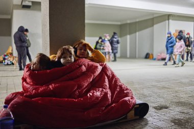 Bir grup küçük çocuk, hava saldırısı sırasında tahta paletin üzerinde sığınakta sessizce oturan kardeşler. Dondurucu gecede bir battaniyeyi paylaşmak. Rus istilası Ukrayna 'ya
