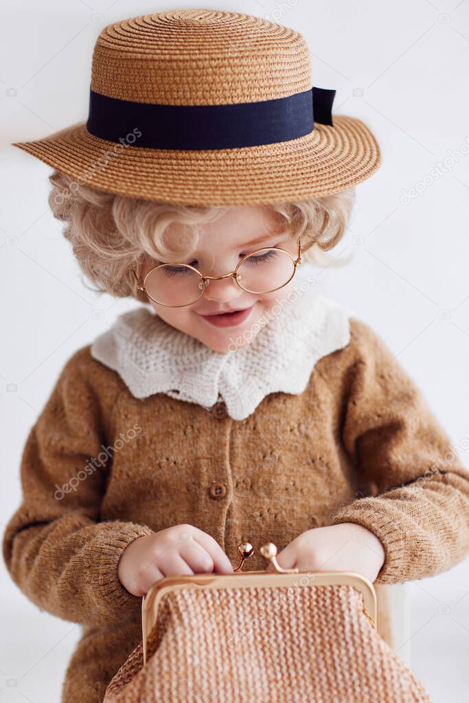 funny baby girl dressed like an old lady rummaging in a purse. cheerful granny looking for money