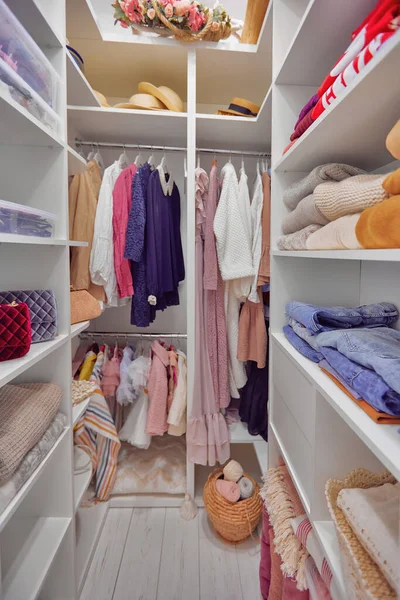 a walk-in wardrobe closet with apparels on hanger rails and shelves