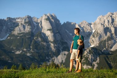 Dağlarda aile zamanı. Baba oğul Avusturya Alplerinde yürüyüş yapıyor.