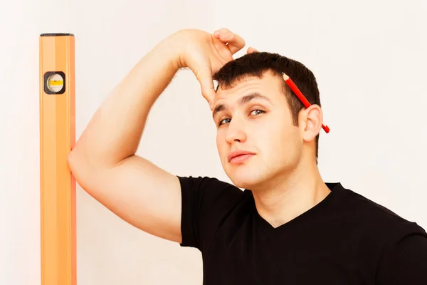 Doordachte jongeman met het meten van hulpmiddel en rood potlood Stockfoto