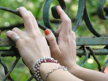 eski bir paslanmış geçit üzerinde oturan genç kızın elleri