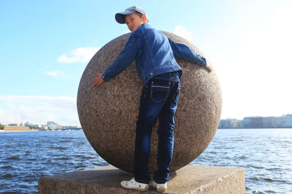 Garçon étreignant boule de granit sur la rivière Neva à Saint-Pétersbourg — Photo